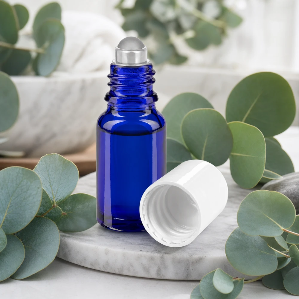 Butelka apteczna niebieska 10ml nakrętka roll-on biała Kobaltowo-niebieska szklana buteleczka apteczna typu roll-on o pojemności 10 ml ze stalową kulką i białą nakrętką na tle marmuru