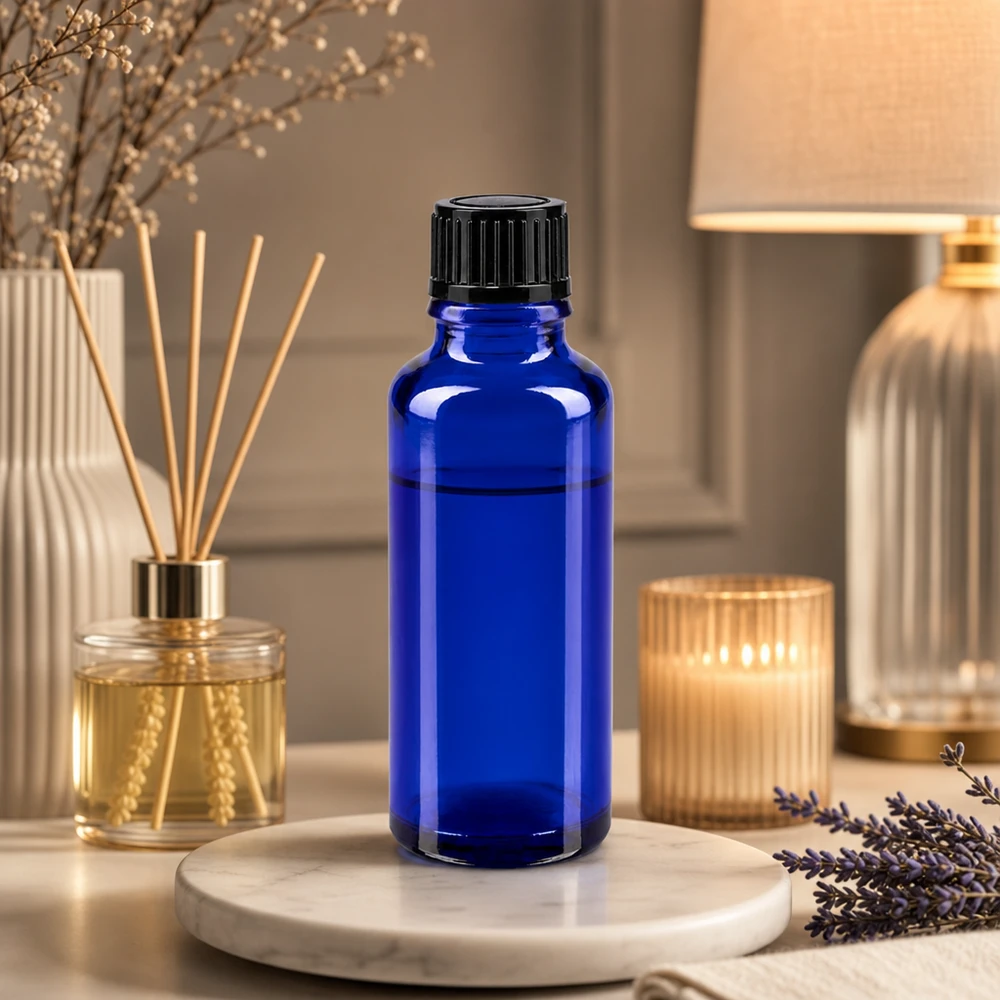 Butelka apteczna niebieska 30ml drip v. 1mm czarny szt Niebieska szklana buteleczka apteczna o pojemności 30 ml z czarnym zakraplaczem, obok lawendy i dyfuzora zapachowego do pomieszczeń