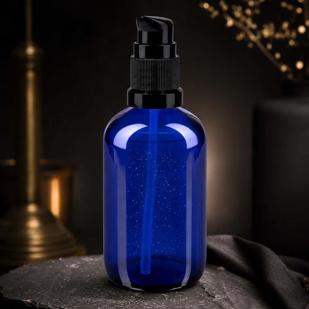 Elegancka butelka z pompką o pojemności 100 ml w kolorze kobaltowym z czarnym dozownikiem na tle ciemnego łupka