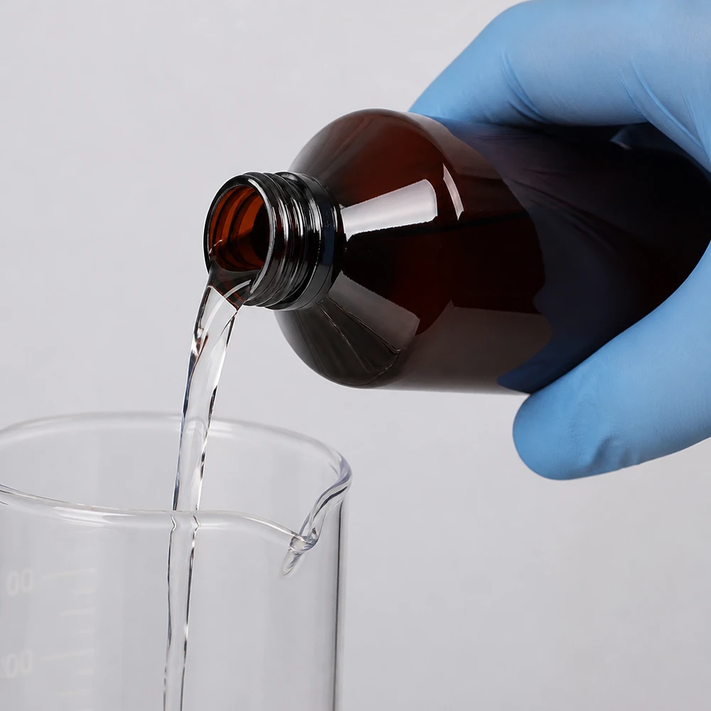 Butelka PET 500 ml z niebieską nakrętką OV Laborantka przelewa przezroczysty płyn z brązowej butelki PET o pojemności 500 ml do zlewki