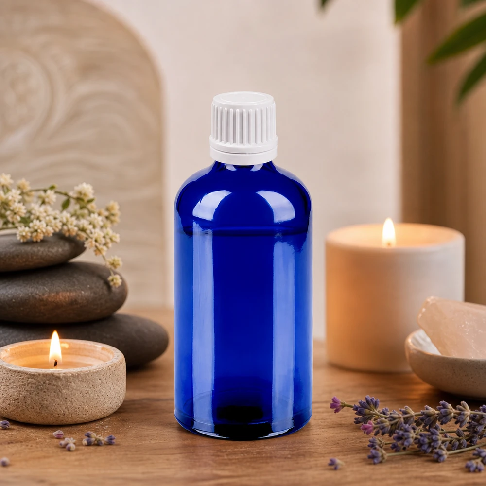 Niebieska szklana butelka o pojemności 100 ml z białym zakraplaczem, idealna do aromaterapii i odnowy biologicznej.