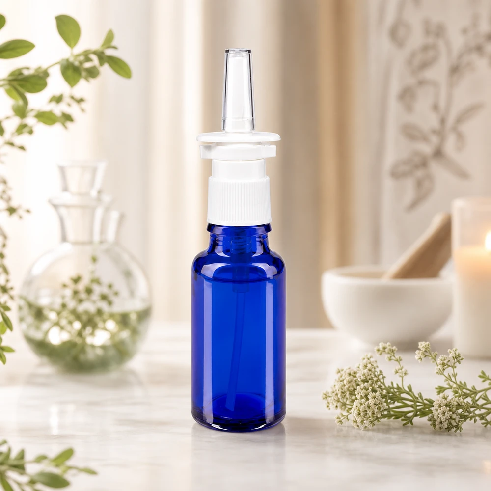 Niebieska butelka farmaceutyczna o pojemności 20 ml z białą pompką do aerozolu do nosa i przezroczystą dyszą aplikatora na tle naturalnej scenerii