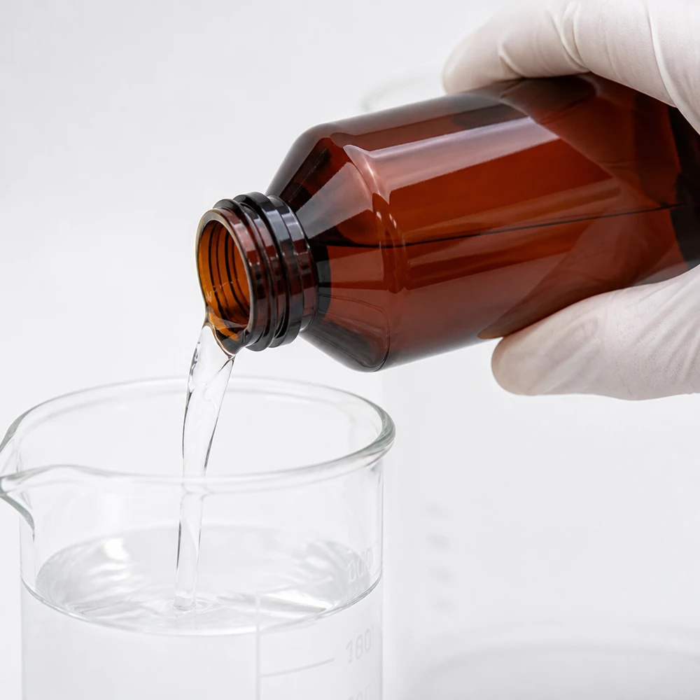 Butelka PET 200 ml z niebieską nakrętką OV Ręka w rękawiczce przelewa przezroczysty płyn z brązowej butelki PET o pojemności 200 ml do szklanej zlewki