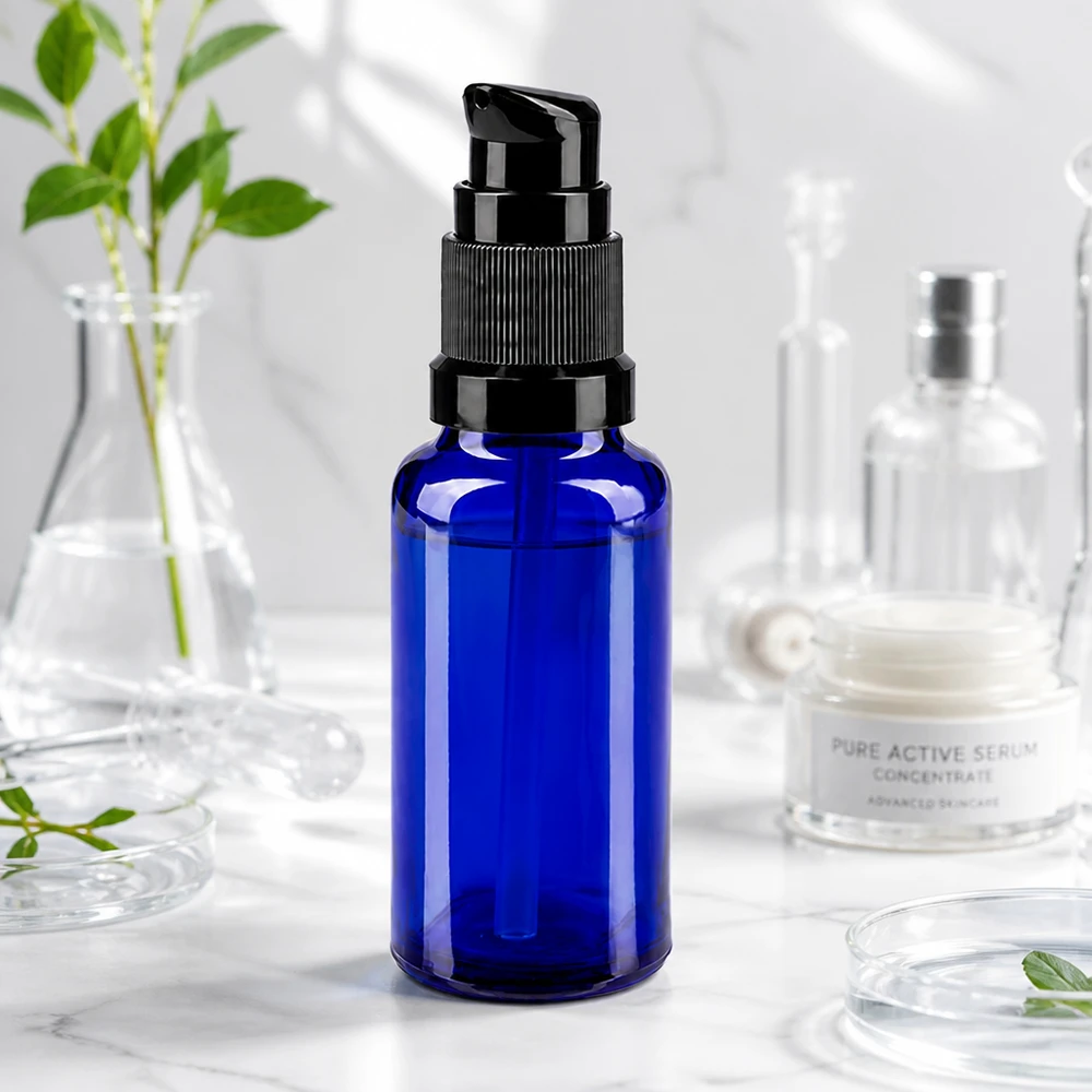 Butelka apteczna niebieska 20ml zakrętka z pompką czarna St Niebieska butelka z pompką o pojemności 20 ml, wykonana ze szkła aptecznego, z czarną głowicą pompki, stojąca na marmurze obok sprzętu laboratoryjnego ze szkła