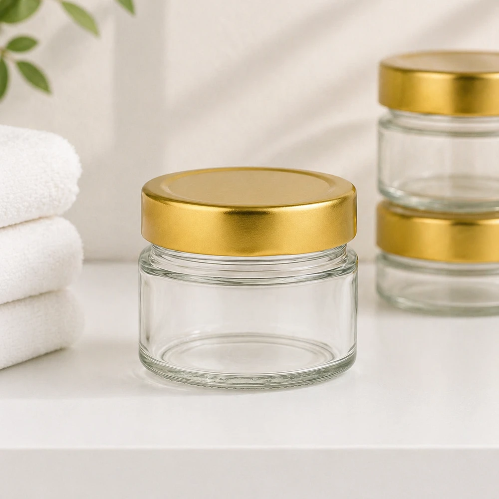 Okrągły słoik o pojemności 80 ml z pokrywką BasicSeal w kolorze złotym z białymi ręcznikami na kosmetyki.