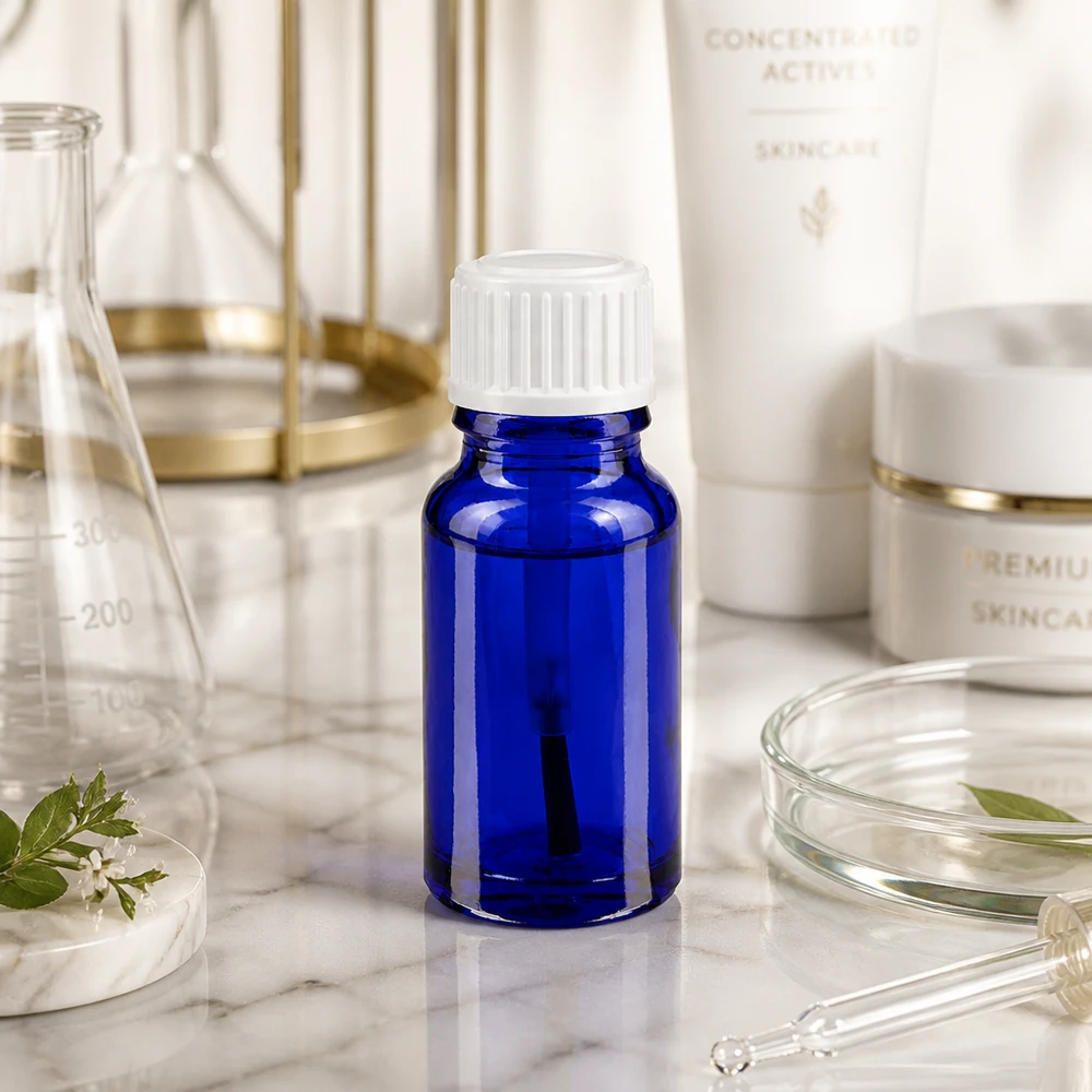 Butelka apteczna niebieska 10ml zakrętka biały pędzelek Mała niebieska szklana buteleczka o pojemności 10 ml z białą zakrętką, stojąca na marmurze wśród sprzętu laboratoryjnego