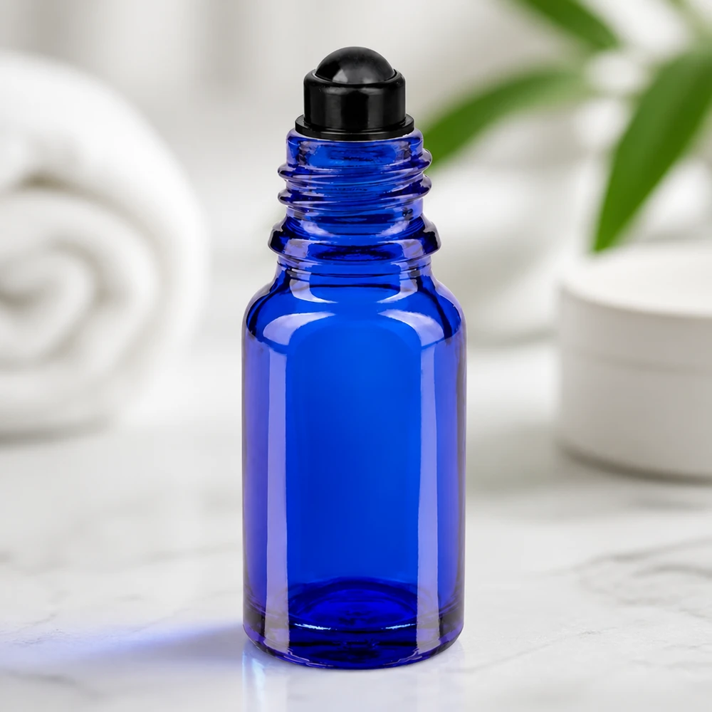 Niebieska szklana buteleczka o pojemności 10 ml z czarną nakładką typu roll-on na tle marmuru na białym tle