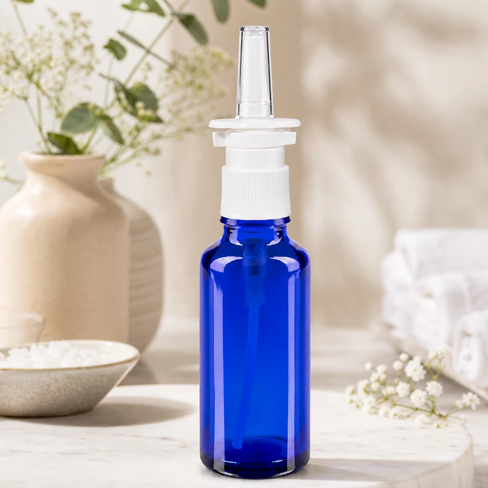 Zbliżenie na butelkę z aerozolem do nosa o pojemności 30 ml, w kolorze kobaltowym, z białą nakrętką z pompką i przezroczystą plastikową końcówką