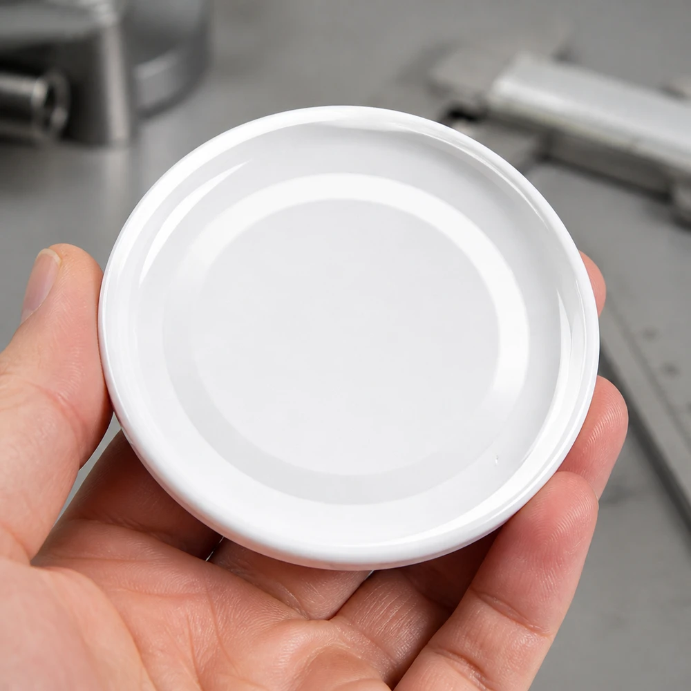 Zbliżenie na białą pokrywkę TO43 o średnicy 43 mm, model BasicSeal UniTwist o okrągłym kształcie, na dłoni