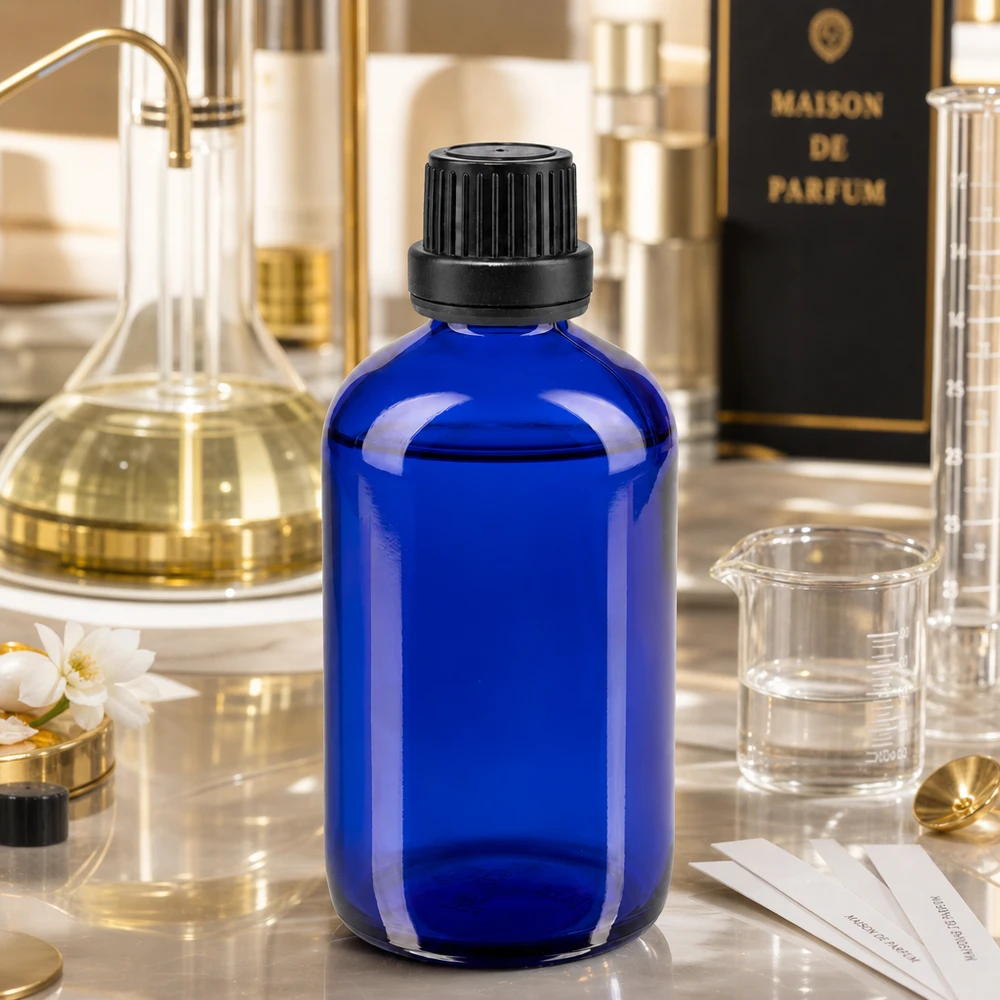 Niebieska szklana butelka o pojemności 100 ml z zakraplaczem w otoczeniu perfumeryjnym z szklanką
