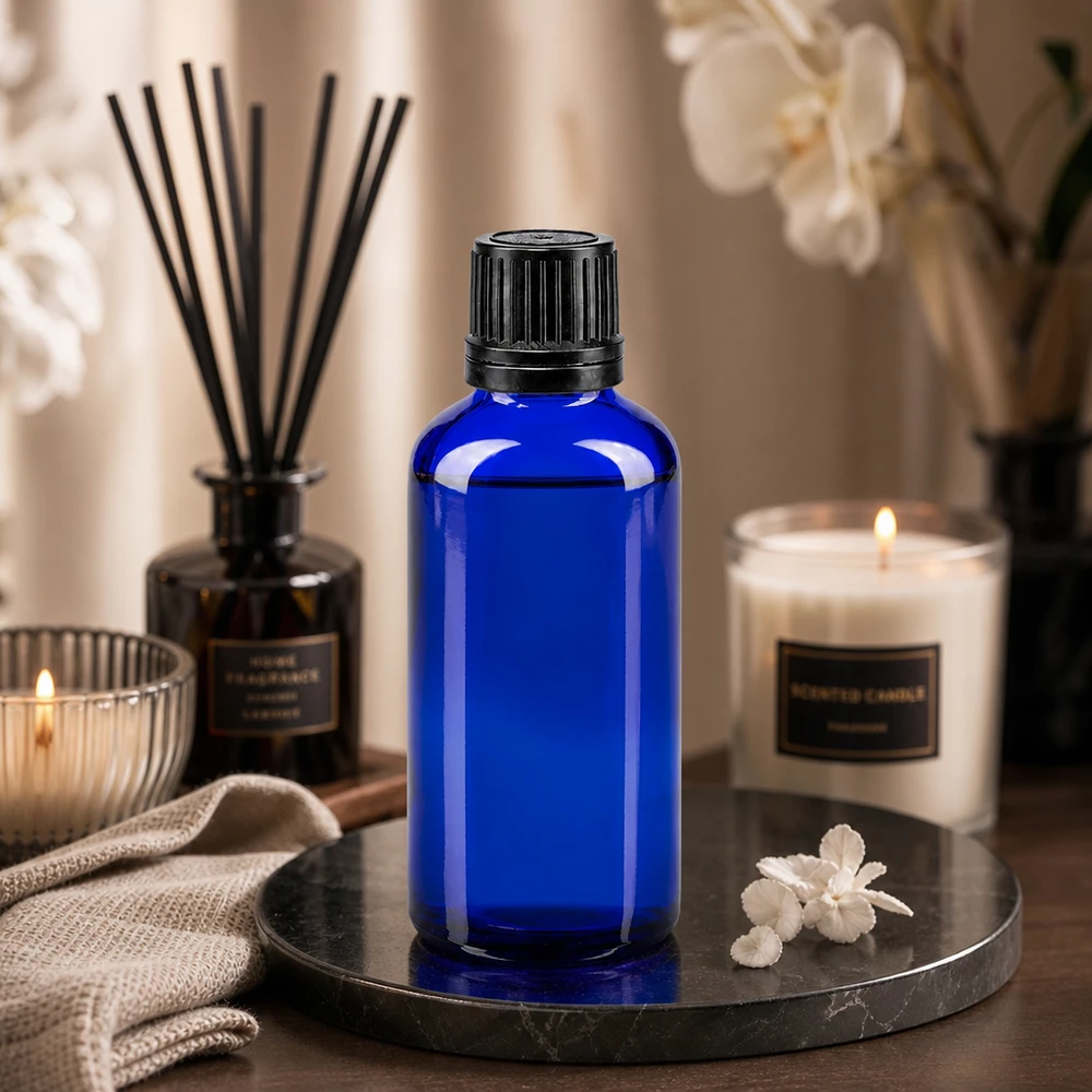 Butelka apteczna niebieska 50ml zakrętka czarny nalewak r. OV Niebieska szklana buteleczka o pojemności 50 ml z czarną zakrętką, umieszczona na marmurowej tacy wraz ze świecami i zapachowym dyfuzorem