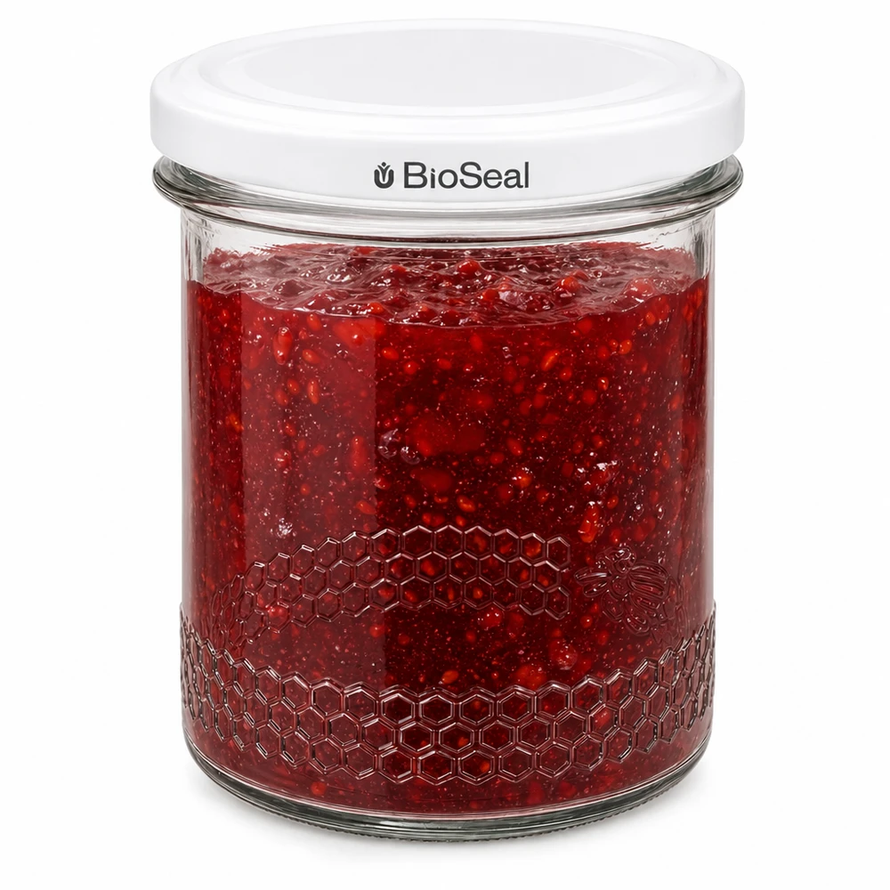 Słoik na przetwory BioSeal 400 ml wypełniony czerwonym dżemem z hermetycznym zamknięciem i wytłoczeniem w kształcie plastra miodu na brzegu słoika.