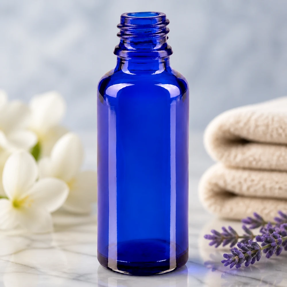 Butelka z zakraplaczem 30 ml DIN 18 NIEBIESKIE SZKŁO Pusta buteleczka apteczna ApoGlas o pojemności 30 ml w kolorze królewskiego błękitu obok gałązki lawendy i białych kwiatów