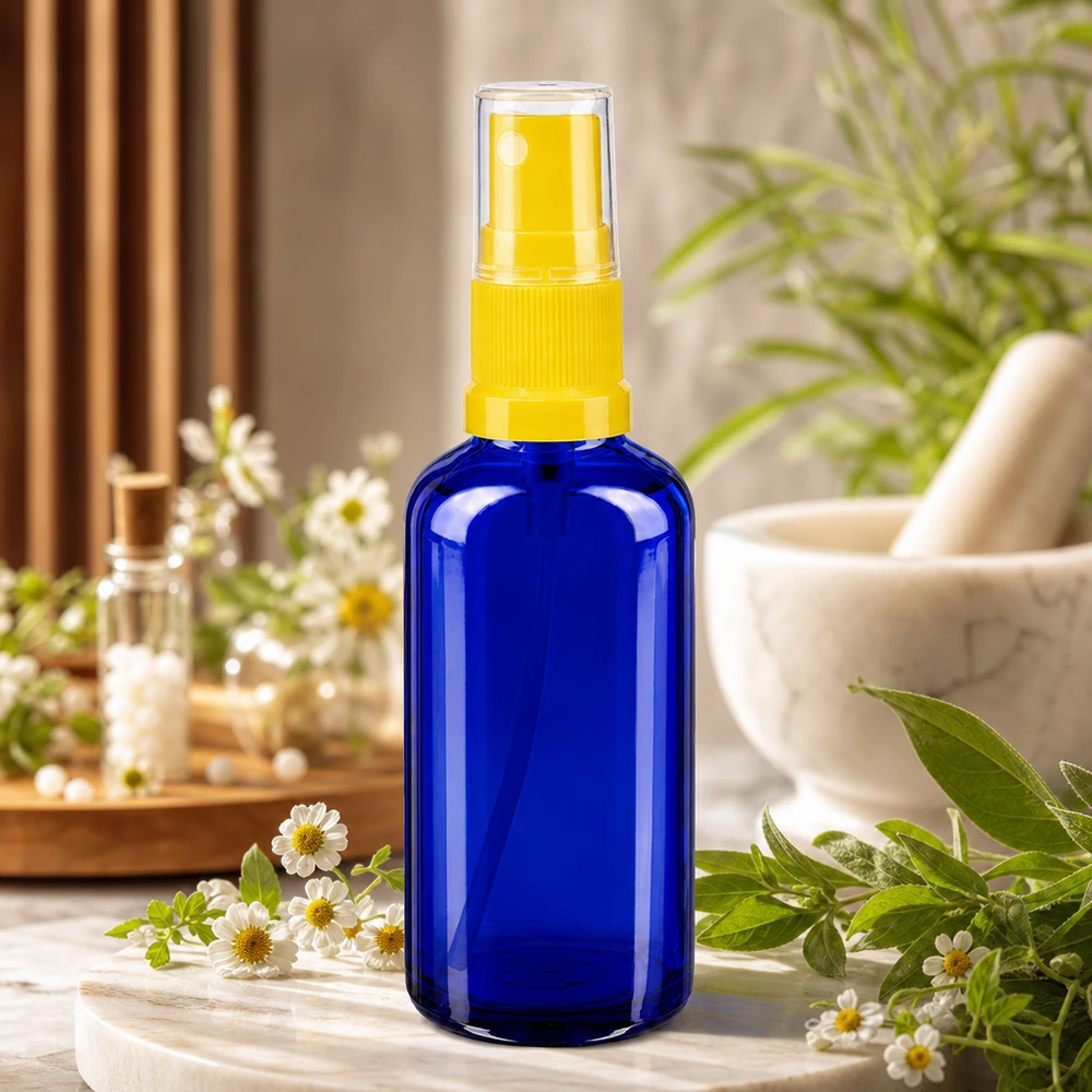 Niebieska butelka aptekarska z rozpylaczem o pojemności 50 ml, wykonana ze szkła chroniącego przed promieniowaniem UV, z przezroczystą głowicą rozpylającą w kolorze żółtym