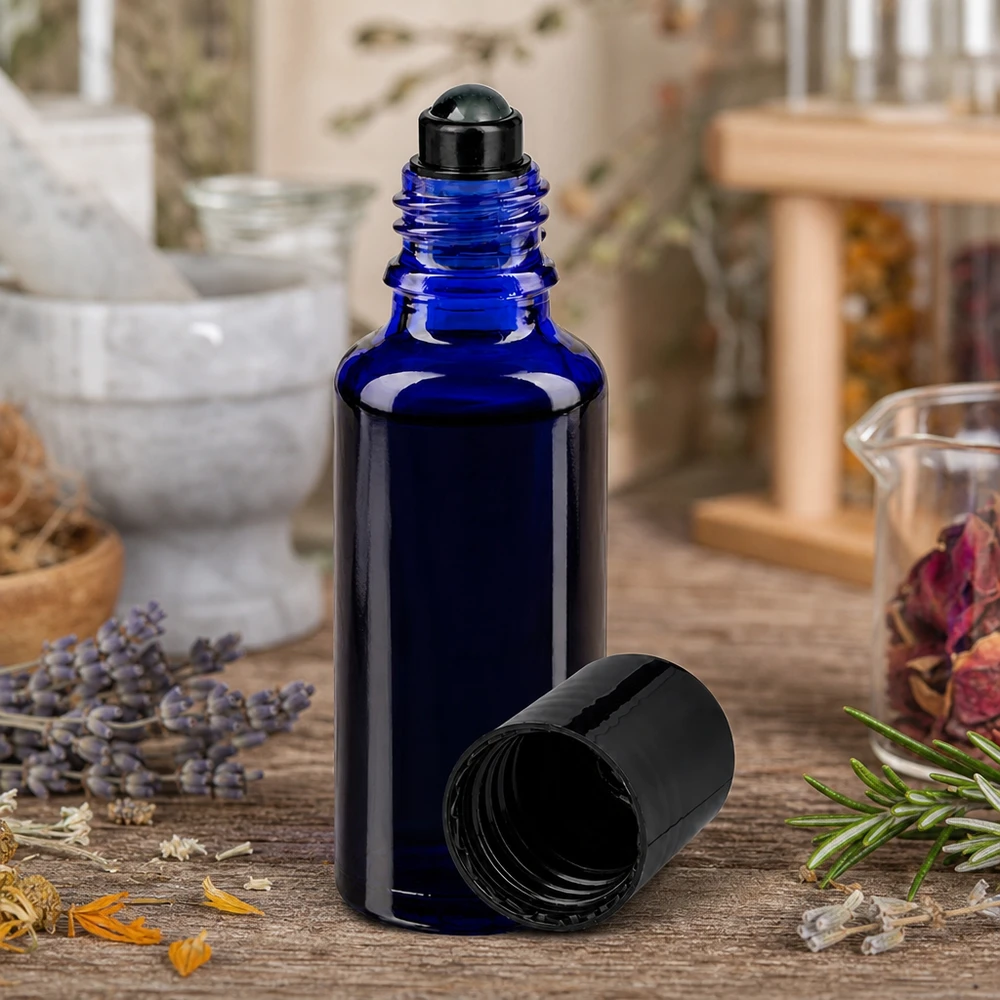 Kobaltowo-niebieska buteleczka ApoGlas o pojemności 30 ml z czarną nakładką typu roll-on, umieszczona wśród suszonych ziół