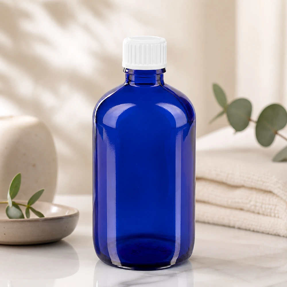 Kobaltowo-niebieska butelka z zakraplaczem o pojemności 100 ml, z zabezpieczoną przed dziećmi zakrętką z białego tworzywa sztucznego