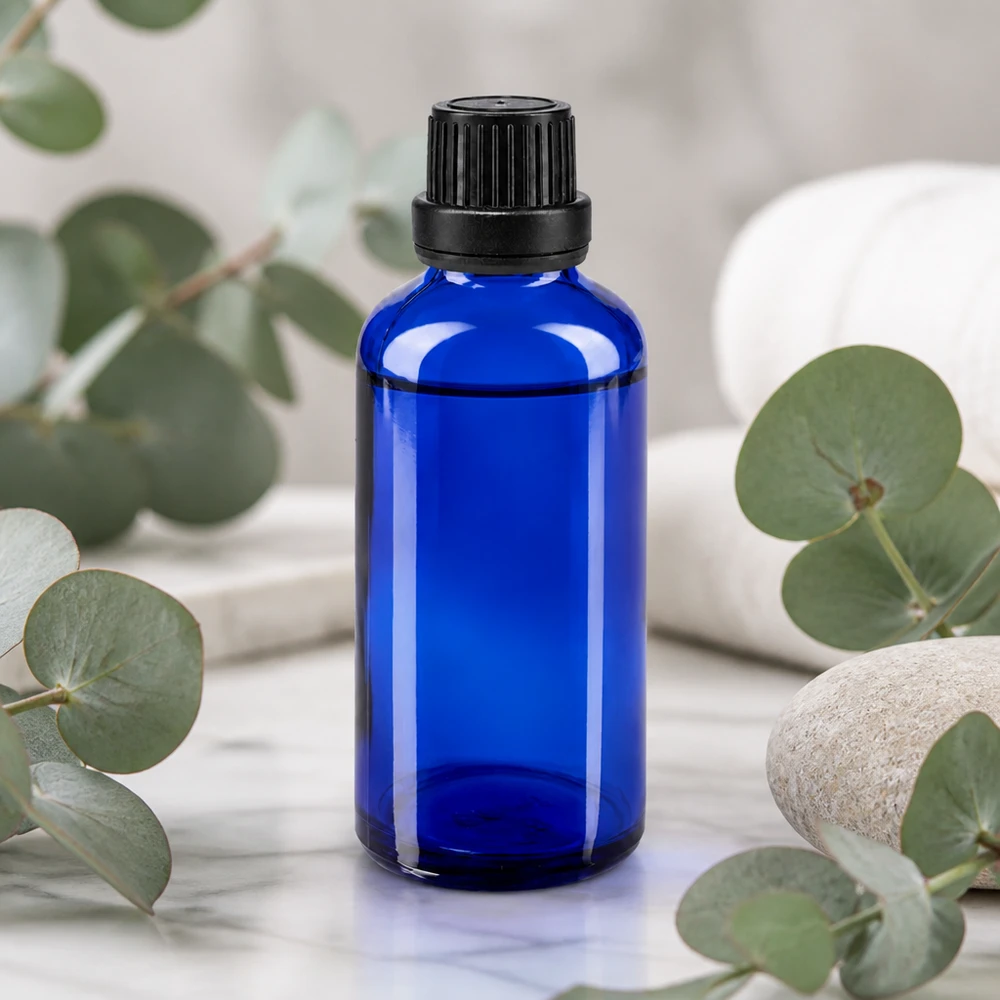 Butelka apteczna niebieska 50ml drip v. Pr. 2mm czarny OV Kobaltowo-niebieska szklana butelka apteczna o pojemności 50 ml z czarnym zamknięciem zabezpieczającym przed dziećmi, przedstawiająca gałązki eukaliptusa