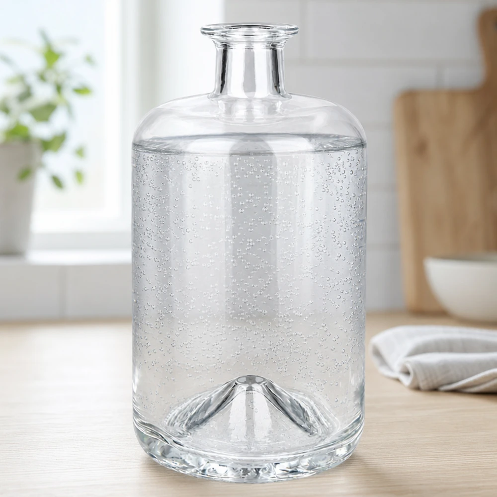 700 ml szklana butelka Sofia wypełniona wodą gazowaną pokazuje bąbelki dwutlenku węgla w jasnym środowisku kuchennym