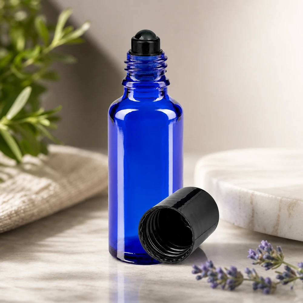 Butelka apteczna niebieska 30ml zakrętka roll-on czarna Szklana buteleczka z kulką o pojemności 30 ml w kolorze kobaltowym z czarną nakrętką, obok lawendy i gałązki rozmarynu