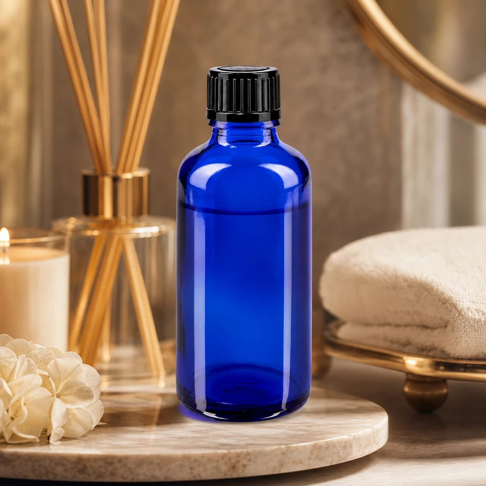 Kobaltowo-niebieska butelka z zakraplaczem o pojemności 50 ml, wykonana ze szkła aptecznego, z czarną zakrętką, w stylu spa