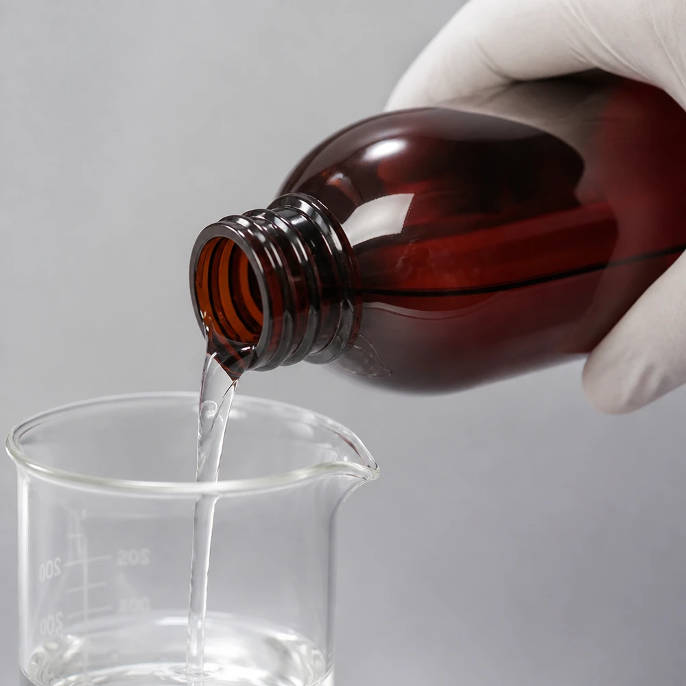 Butelka PET 250 ml z białym karbowanym OV Osoba w rękawiczkach wlewa przezroczysty płyn z brązowej butelki PET do zlewki