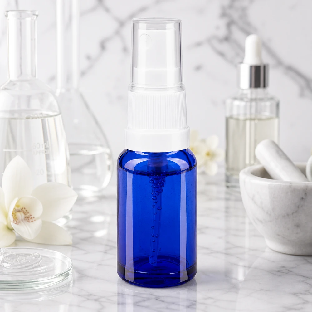 Butelka apteczna niebieska 10ml spray top biały Butelka z atomizerem o pojemności 10 ml, wykonana z niebieskiego szkła aptecznego, z białym atomizerem na marmurowym tle w stylu laboratoryjnym