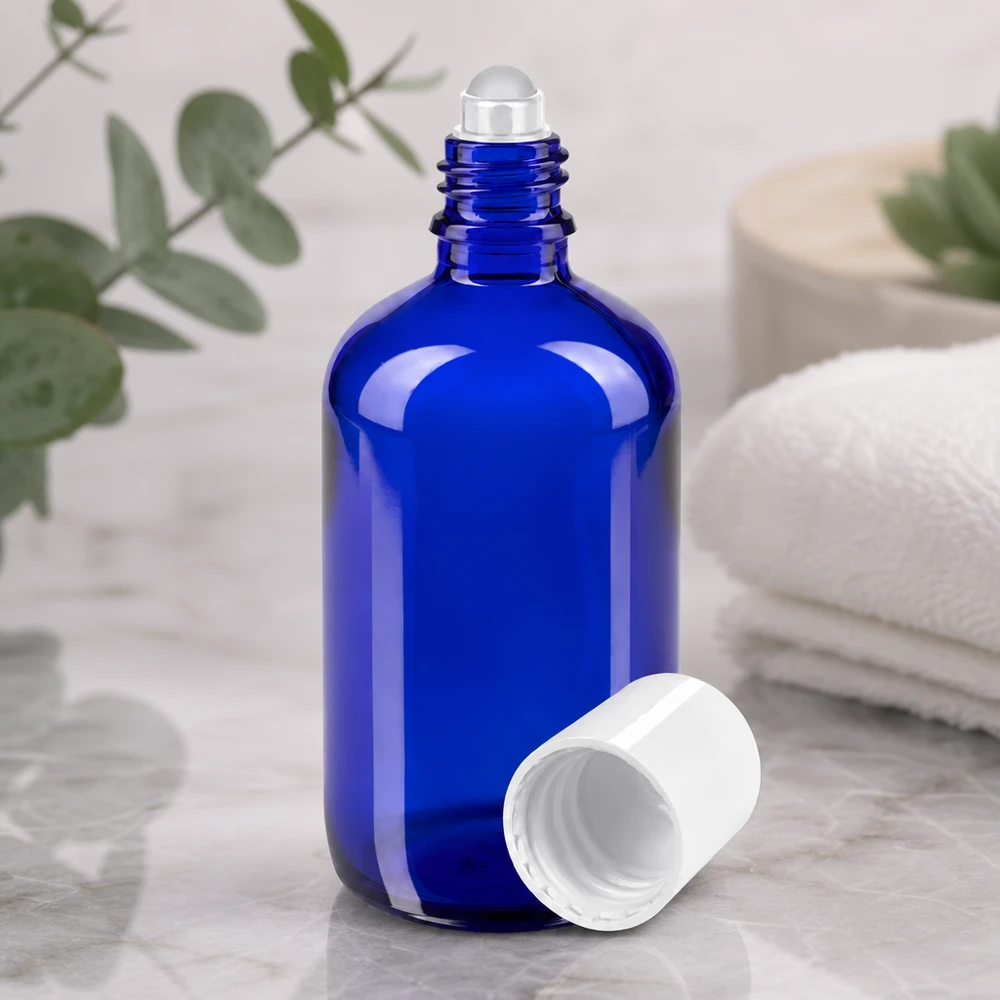 Butelka apteczna niebieska 100ml nakrętka roll-on biała Otwarty flakonik z kulką o pojemności 100 ml w kolorze kobaltowym z przezroczystą szklaną kulką i białą plastikową nakrętką