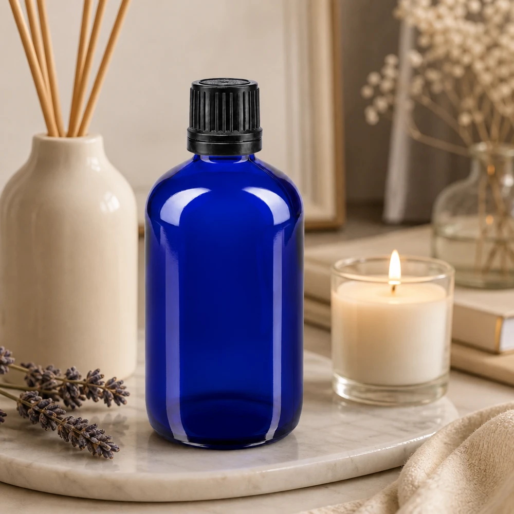 Butelka apteczna niebieska 100ml zakrętka czarny nalewak r. OV Niebieska szklana buteleczka o pojemności 100 ml z czarnym zakraplaczem, umieszczona na marmurowej podstawce z lawendą i świecą