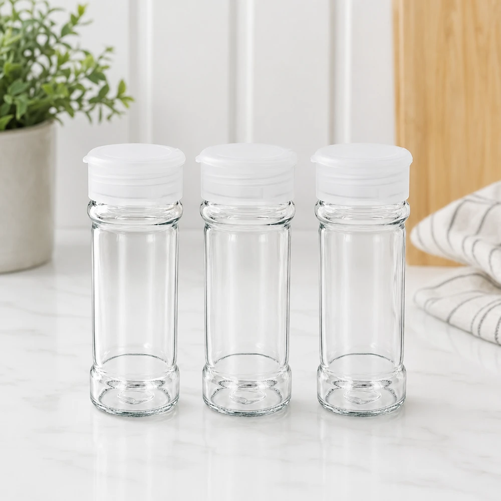Słoik na sól/przyprawy 100 ml z dozownikiem, biały Trzy puste słoiki na przyprawy z przezroczystego szkła o pojemności 100 ml z białymi pokrywkami z dozownikiem, ustawione na marmurowym blacie