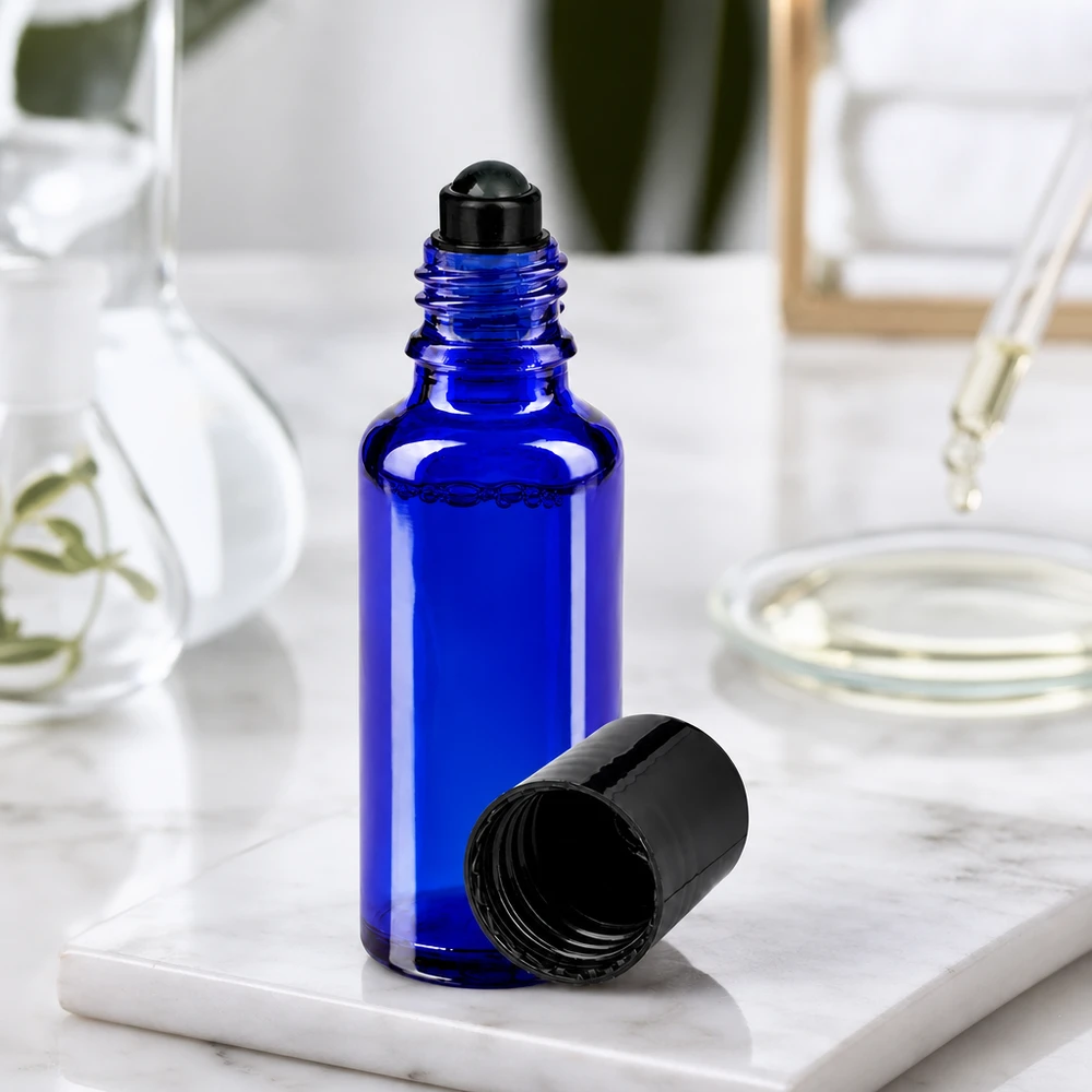 Szklana buteleczka o pojemności 30 ml w kolorze kobaltowym z czarną nakładką typu roll-on i zdejmowaną zakrętką