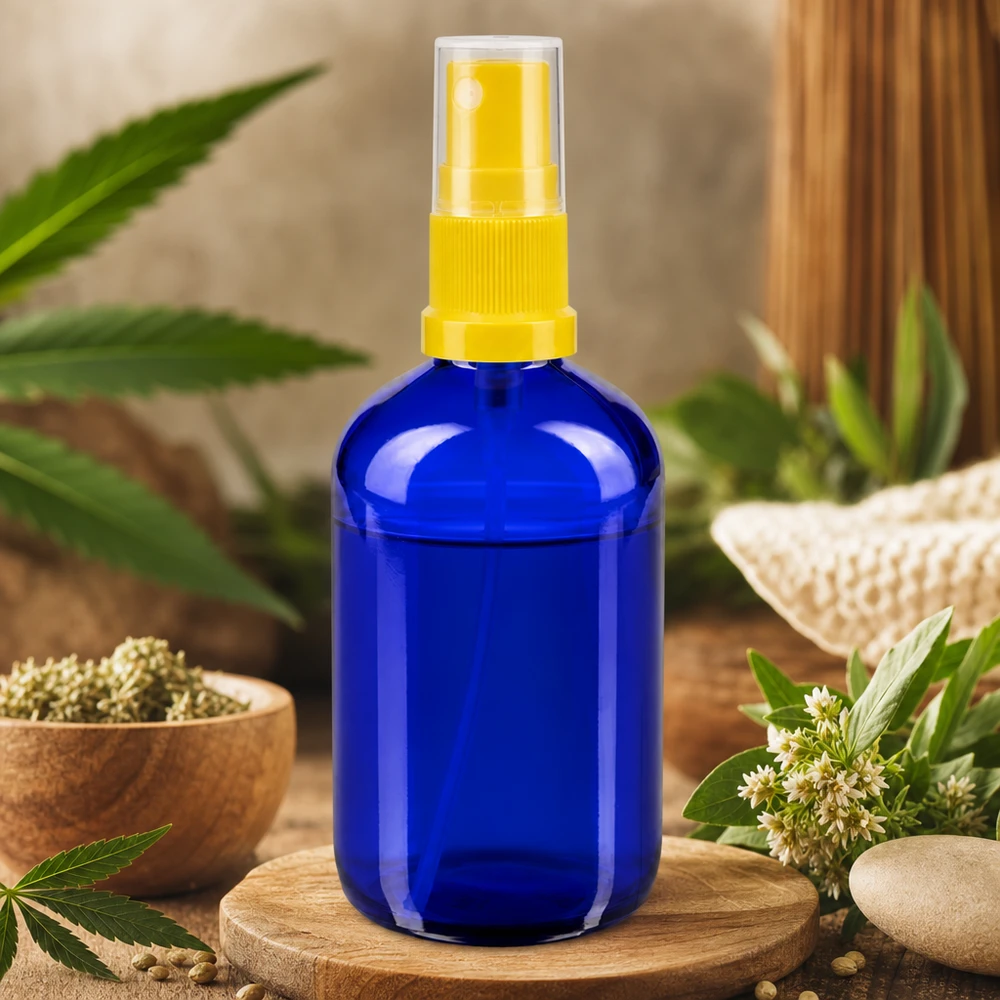 Niebieska szklana butelka o pojemności 100 ml z żółtą głowicą rozpylającą, otoczona motywem konopi i naturalnych ziół