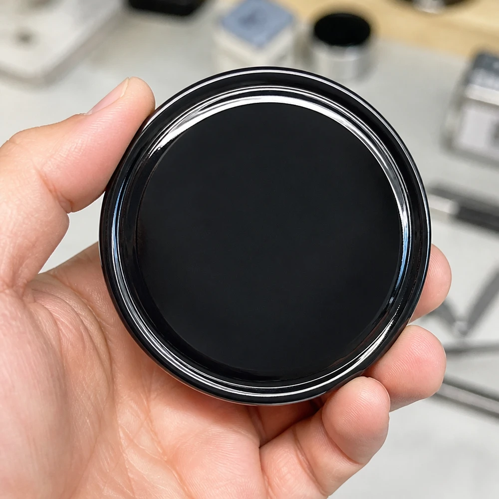 Zbliżenie na błyszczącą czarną zakrętkę BasicSeal 70 mm TO70 UNiTWIST na dłoni