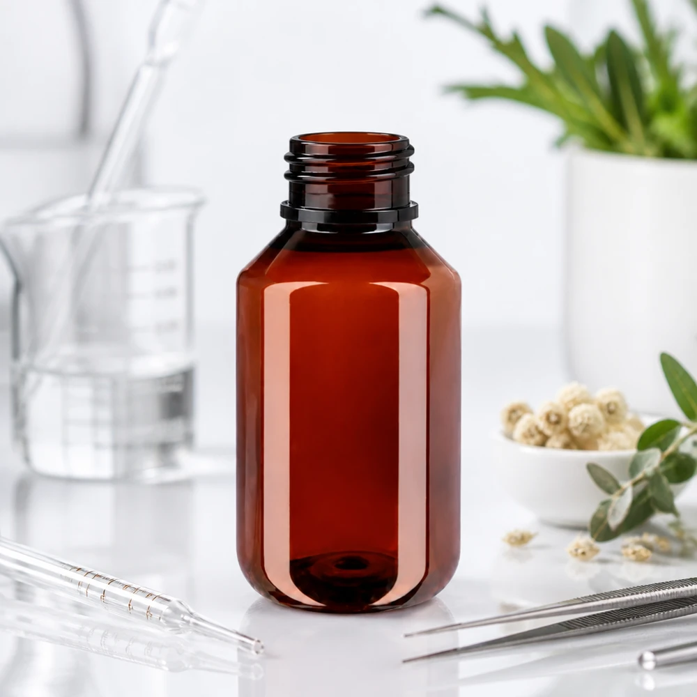 Butelka PET 100 ml z białą nakrętką typu flip-top. Brązowa butelka PET o pojemności 100 ml bez nakrętki, obok ziół leczniczych i pipety laboratoryjnej