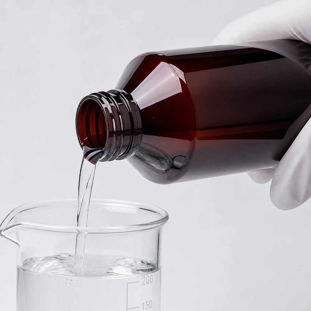Butelka PET 750 ml z białym zamknięciem typu flip-top. Laborant przelewa przezroczysty płyn z brązowej butelki PET o pojemności 750 ml do szklanej zlewki