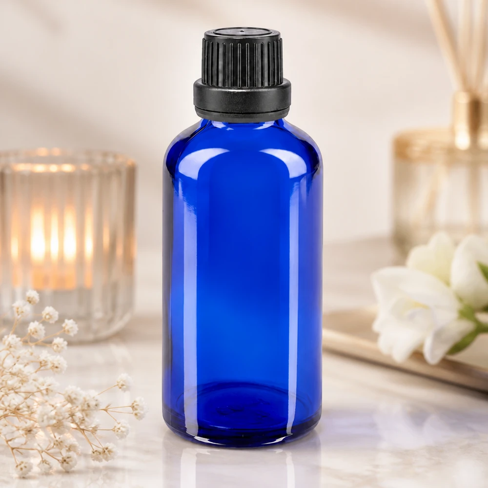 Butelka apteczna niebieska 50ml drip v. Pr. 2mm czarny OV Szklana buteleczka o pojemności 50 ml w kolorze kobaltowym z czarną zakrętką i kroplomierzem, obok świecy i kwiatów