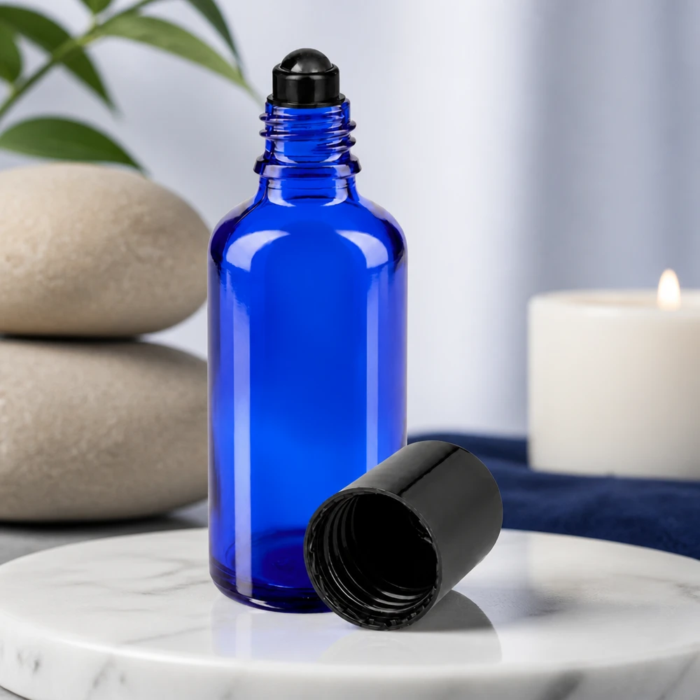 Niebieska szklana buteleczka o pojemności 50 ml z czarnym aplikatorem typu roll-on i zdjętą nakrętką na tle marmuru