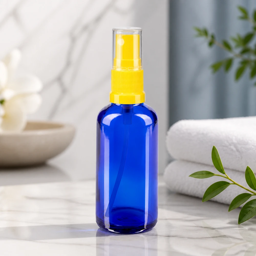 Niebieska szklana buteleczka apteczna o pojemności 50 ml z żółtym rozpylaczem na tle marmuru