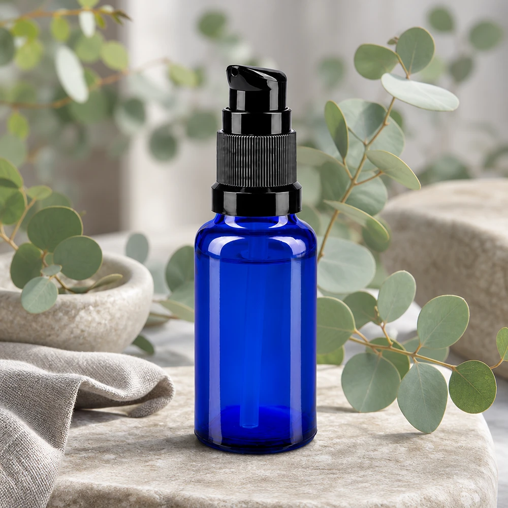 Butelka apteczna niebieska 20ml zakrętka z pompką czarna St Niebieska szklana buteleczka apteczna o pojemności 20 ml z czarną pompką dozującą na tle gałązek eukaliptusa