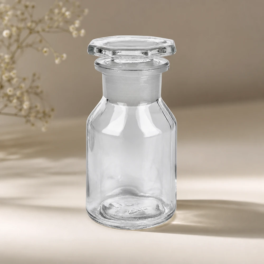 Butelka z wypukłą przednią ścianką, 50 ml, przezroczysta, z szeroką szyjką i fasetowanym szklanym korkiem, przeznaczona dla aptek i kolekcjonerów