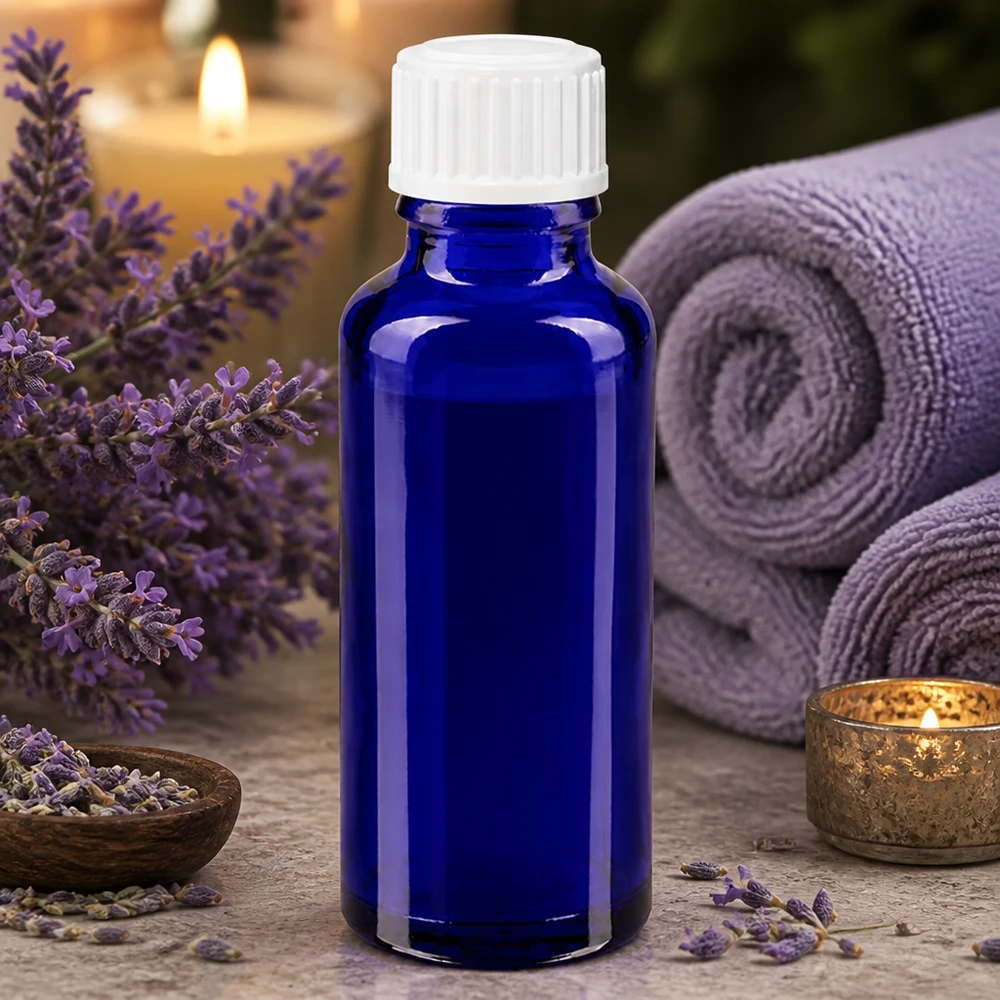 30 ml niebieska szklana buteleczka z białą nakładką z kroplomierzem o średnicy 3 mm, otoczona kwiatami lawendy i akcesoriami spa