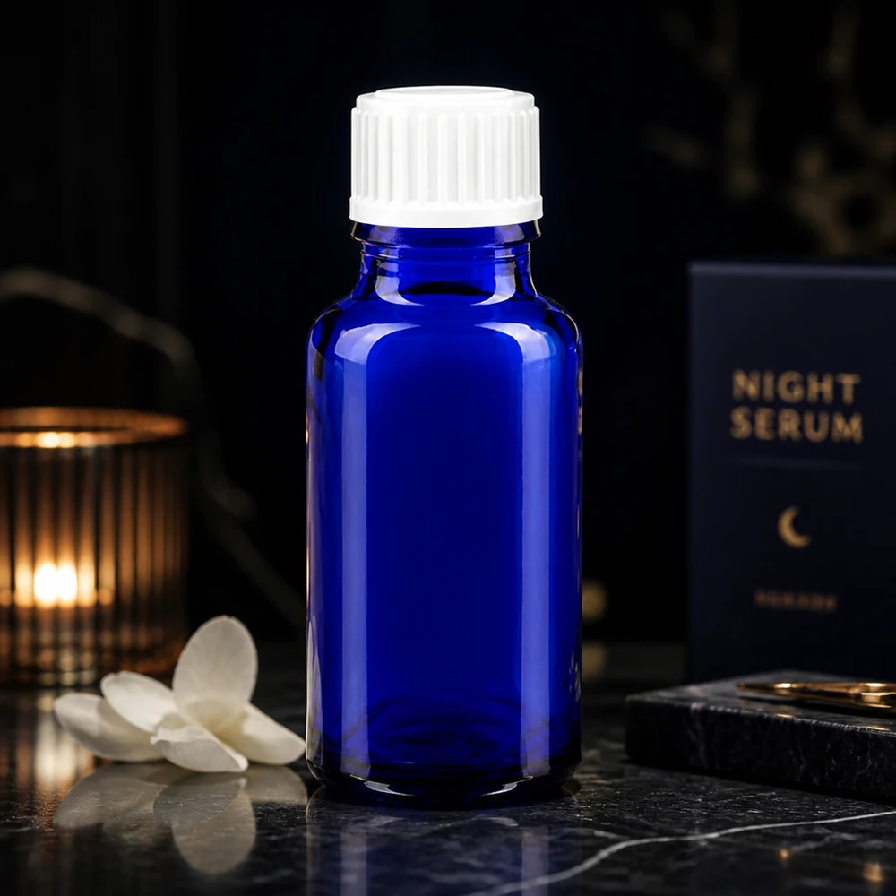 Szklana buteleczka o pojemności 20 ml w kolorze kobaltowym z białą nakrętką obok opakowania serum na noc na ciemnym tle