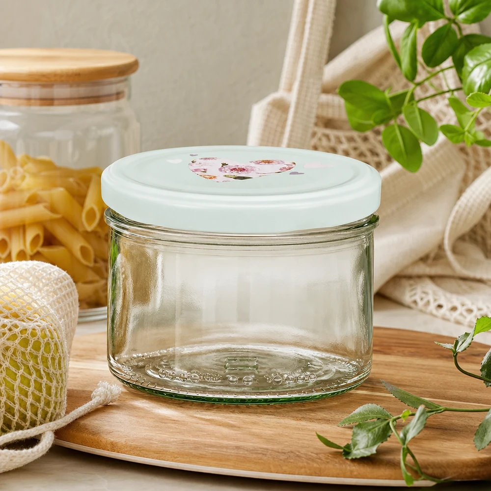 Szklanka cylindryczna 230 ml + pokrywka BasicSeal serce miętowa Słoik cylindryczny 230 ml z pokrywką BasicSeal serce miętowe pusty na drewnianej tacy z workiem jutowym na makaron i zielonymi roślinami
