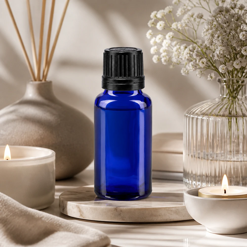 Butelka z niebieskiego szkła o pojemności 20 ml z zakrętką OV na marmurowym postumencie w relaksującej atmosferze wellness