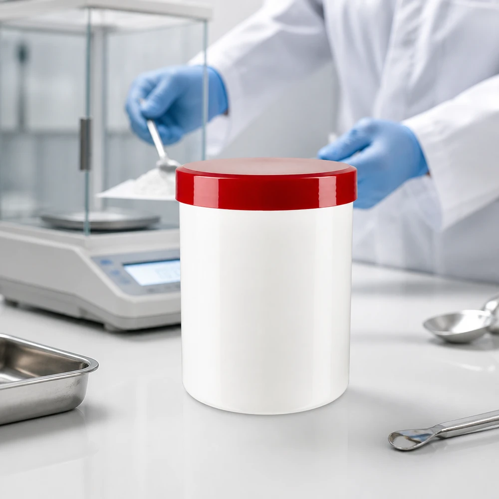 Słoik na maść 150 g, biały z czerwoną pokrywką, obok wagi analitycznej i szpatułki laboratoryjnej w pomieszczeniu czystym