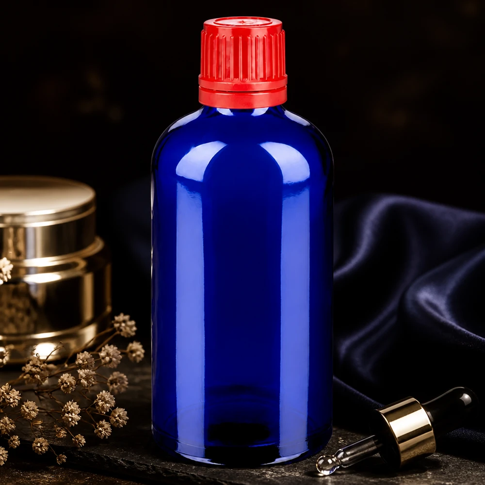 Elegancka butelka z zakraplaczem BlueLine UT18 o pojemności 100 ml wykonana z kobaltowego szkła z czerwoną nakrętką z zabezpieczeniem przed manipulacją.