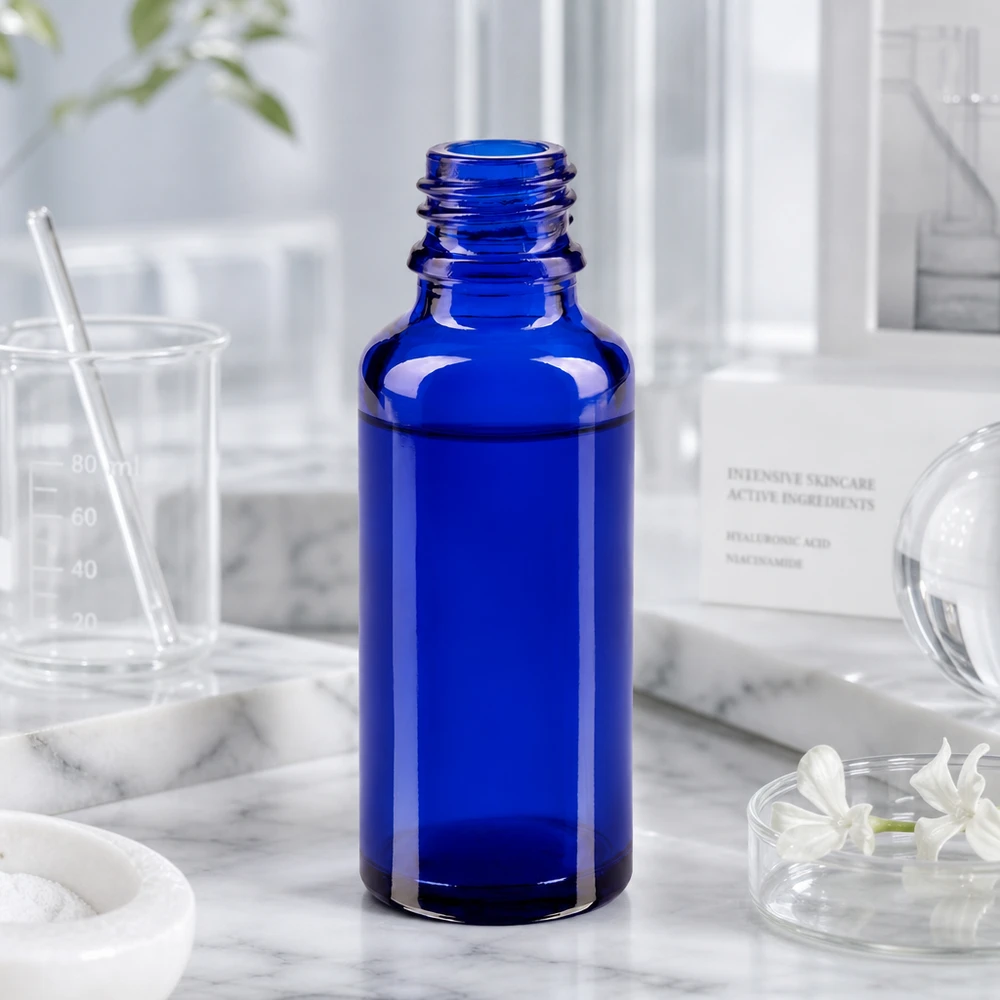 Kobaltowo-niebieska butelka ApoGlas o pojemności 30 ml w laboratorium wraz z miarką i składnikami do pielęgnacji skóry