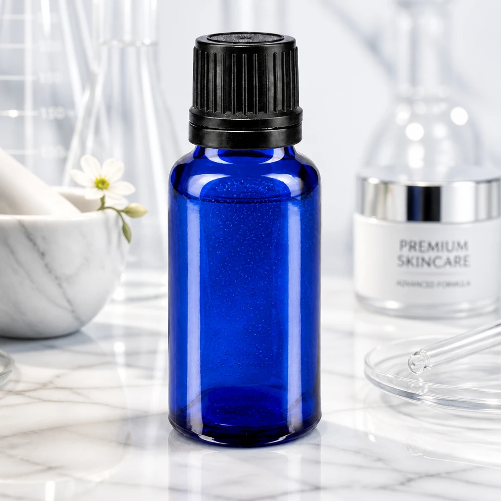 Butelka apteczna niebieska 20ml kroplówka v. Pr. 1mm czarny OV Niebieska szklana buteleczka o pojemności 20 ml z czarną zakrętką na tle marmurowym, przed zestawem naczyń laboratoryjnych