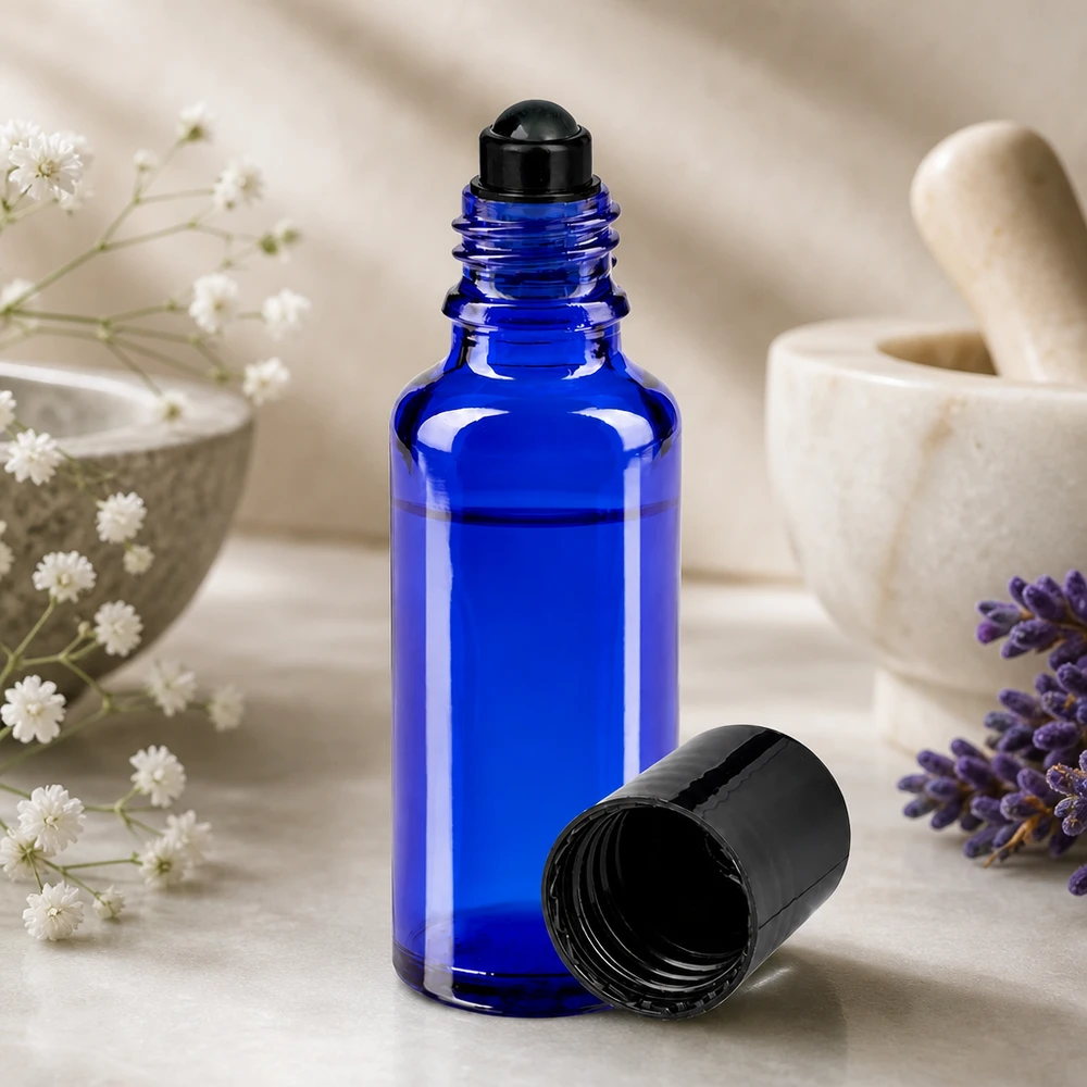 Niebieska buteleczka apteczna z kulką o pojemności 30 ml, z czarną kulką, obok lawendy i moździerza