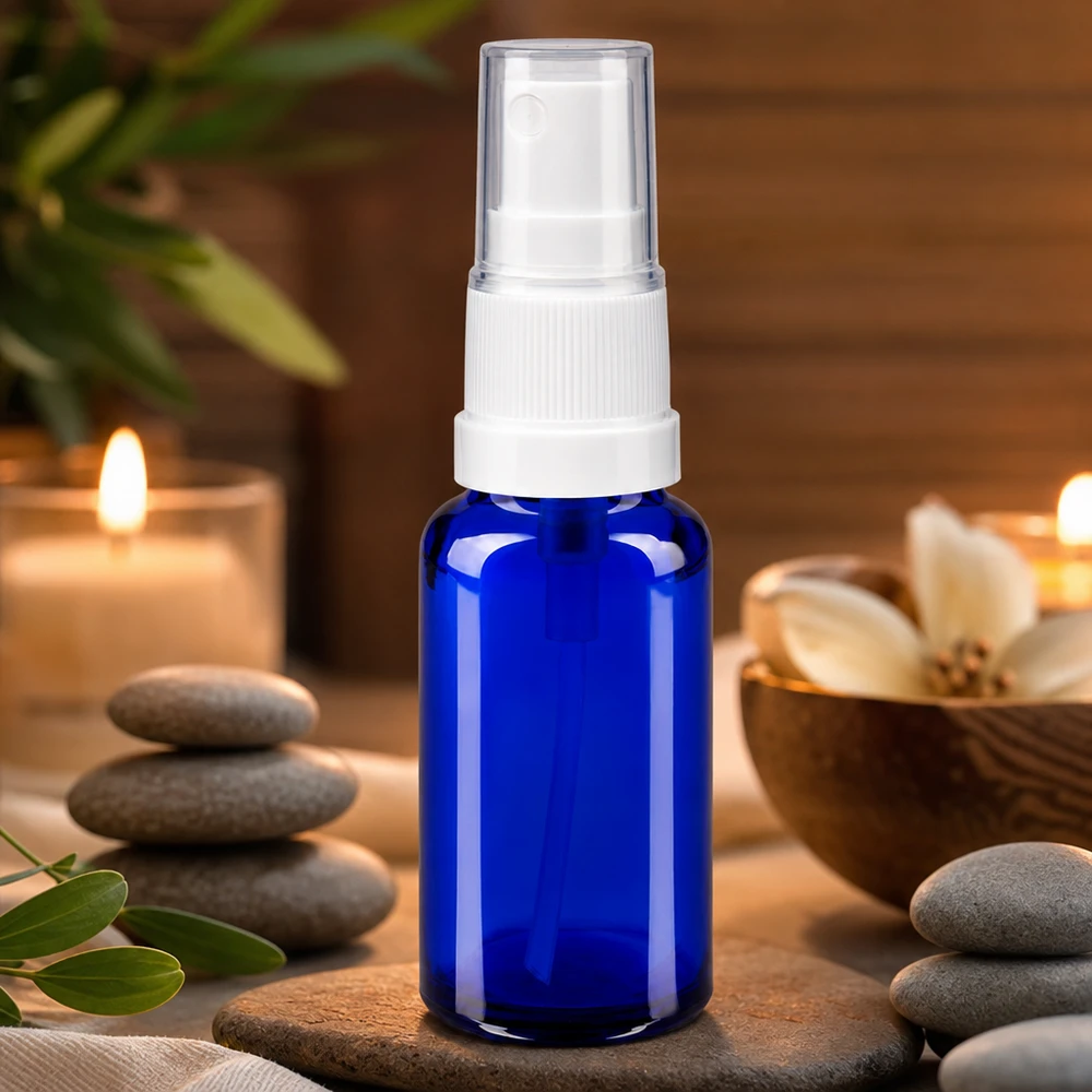 Niebieska szklana butelka apteczna z atomizerem o pojemności 20 ml z białym pompowym rozpylaczem, w atmosferze wellness-spa z świecami