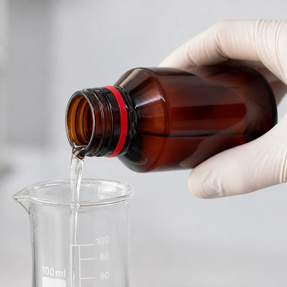 Laborant napełnia brązową butelkę PET o pojemności 50 ml przezroczystym płynem z probówki